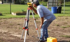 Land surveyor using surveying equipment while working on property boundaries for a boundary survey