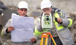 Surveyors reviewing site plans beside a total station, illustrating ALTA Table A survey planning in Virginia